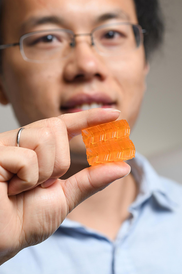 Georgia Tech postdoctoral fellow Xiao Kuang demonstrates the compressibility of origami structures created through Digital Light Processing 3D printing. (Photo: Christopher Moore)